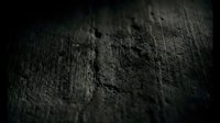 Dark textured surface with rough weathered material showing cracks and erosion patterns in moody atmospheric lighting for backgrounds.