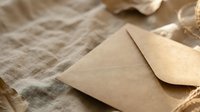 Kraft paper envelope with wax seal on linen fabric background for wedding invitations, stationery design, correspondence and postal services.
