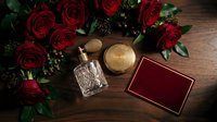 Elegant red roses bouquet with luxury perfume bottle and jewelry box on rustic wooden background for romantic occasions and gift concepts.