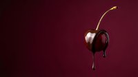 Fresh ripe cherry with chocolate dripping down on dark red background for dessert and confectionery advertising.
