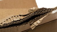 Corrugated cardboard sheets and crumpled kraft paper strips arranged on brown packaging material, suitable for shipping, recycling, and sustainable packaging design projects.