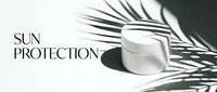 Cosmetic jar with sun protection cream displayed with tropical palm leaves and shadow on white background for skincare marketing.