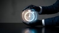 Young adult male with light skin tone wearing dark business attire holding glowing digital clock interface in hands, representing time management, deadline scheduling, and business efficiency concepts.