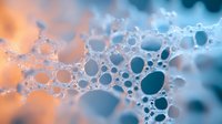 Macro photography of soap bubbles forming abstract pattern with orange and teal gradient background. Artistic close-up shows delicate foam structure.