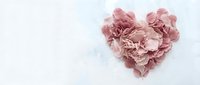 Heart-shaped arrangement of delicate pink rose petals on soft white background for romantic wedding and Valentine's Day designs.