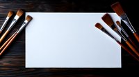Blank white paper sheet with professional art brushes arranged on dark wooden background, creating artistic workspace composition for painting and drawing.