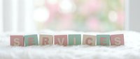 Wooden alphabet blocks spelling SERVICES on white surface with soft blurred floral background for business and professional concepts.
