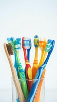 Colorful toothbrushes collection in glass holder on white background for dental hygiene and oral care concepts.