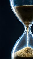 Golden sand flowing through elegant hourglass against dark background symbolizing time passage, deadline pressure, and life moments for business concepts.