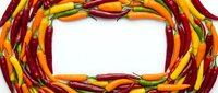Hot chili peppers in red, yellow and orange arranged in a circular frame on white background. Culinary ingredient for cooking.