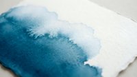Abstract watercolor painting with flowing blue and white tones creating organic shapes on textured paper surface for artistic projects and creative designs.