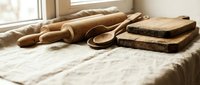 Rustic wooden kitchen utensils and cutting boards arranged on marble countertop near window with natural lighting for culinary cooking preparation.