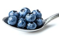 Fresh ripe blueberries on silver spoon against white background, macro food photography showing juicy texture and natural bloom on berries.