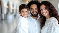 Happy Hispanic family with young son smiling at camera, wearing white clothes. Parents with curly dark hair and bright authentic smiles embrace child in modern interior.