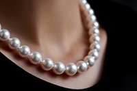 Elegant white pearl necklace on soft skin background with selective focus and shallow depth of field, showcasing luxury jewelry and fine accessories.
