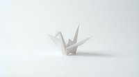 White origami paper crane folded from single sheet on clean white background. Minimalist Japanese art form symbol of peace and hope for creative projects.