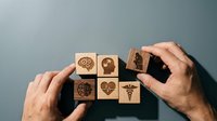 Healthcare concept with wooden blocks featuring medical symbols arranged by hands for insurance and wellness planning.