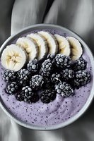 Fresh blackberries and sliced banana arranged on purple smoothie bowl with yogurt base and chia seeds, captured in moody lighting for food photography.