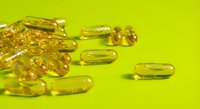 Golden vitamin E capsules scattered on bright green background for health and wellness supplement marketing materials.