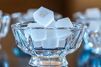 White sugar cubes stacked in elegant crystal glass bowl with geometric pattern design, macro photography with soft focus background for food styling.