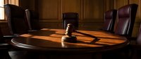 Wooden gavel on polished conference table in elegant boardroom with leather chairs. Corporate law, legal decisions, business meetings and judicial proceedings.