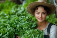 Young woman in straw hat and overalls harvesting fresh kale in organic garden. Sustainable farming and healthy eating concept.