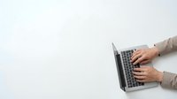 Hands typing on laptop computer keyboard from above view with clean white background for business and technology concepts.