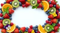 Fresh mixed berries and fruits frame with strawberries, blueberries, raspberries, kiwi and orange slices on white background with copy space center.