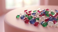 Colorful precious gemstones scattered on white surface including emeralds, rubies, sapphires and diamonds for jewelry making and luxury accessories design.