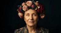 Elegant senior woman wearing ornate floral crown with roses and burgundy blooms against dark background for portrait photography and artistic projects.