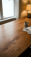Wooden desk with coffee mug and notebook by bright window in warm home office, ideal for workspace and productivity content.