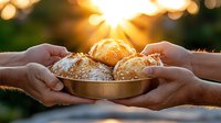 Fresh baked buns with sesame seeds in wooden bowl shared between hands against golden sunset bokeh background, warm evening atmosphere.