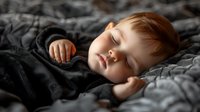 Peaceful sleeping toddler boy with red hair lying in bed under gray blanket, soft natural light falling on face, dreamy atmosphere for parenting and childhood concepts.