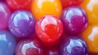 Colorful glossy candy spheres with vibrant red, purple, orange and yellow hues creating sweet confectionery display for dessert and treat concepts.