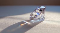 Brilliant cut diamond on white silk fabric casting rainbow reflections and shadows in soft natural lighting, luxury jewelry concept for engagement and wedding designs.