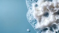 White soap foam and bubbles on turquoise blue background with soft focus macro photography, abstract minimalist composition for cosmetic and cleaning products.
