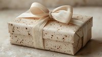Elegant gift wrapped in cream speckled paper with satin ribbon bow, photographed in soft natural light. Minimalist festive composition on neutral background.