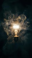 Glowing lightbulb surrounded by golden energy particles and human silhouettes with brain symbols, representing innovation, creativity, and intellectual ideas for business and technology concepts.