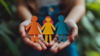 Hands holding colorful paper cutout figures of women holding hands, symbolizing unity, diversity, sisterhood and female empowerment against blurred natural background.