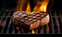 Juicy grilled beef steak with rosemary on flaming barbecue grill, grill marks and charred exterior showing professional cooking technique. For food industry.