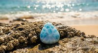 Blue larimar gemstone resting on weathered rock formation at tropical beach with turquoise ocean waves and golden sand creating serene coastal scene.