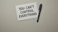 Motivational note with you can't control everything message on beige background with black pen for mindfulness and mental health awareness.