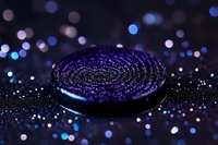 Chocolate sandwich cookie with purple sparkles and glitter on dark background with bokeh lights creating magical atmosphere for food photography and design.