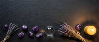 Lavender sprigs with amethyst crystals and candle on dark slate surface for aromatherapy spa wellness meditation relaxation healing energy spiritual practices.