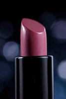 Close-up of pink metallic lipstick against dark bokeh background, showcasing luxurious cosmetic texture with subtle sparkles and professional studio lighting.
