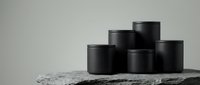 Black cosmetic jars arranged on marble surface against neutral background for skincare product packaging and beauty brand marketing.