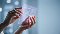 Woman with dark skin tone holding transparent holographic display showing financial graph data, representing digital technology, business analytics, and future innovation in financial markets.
