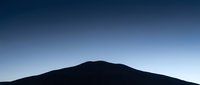 Silhouette of a mountain peak against a clear blue gradient sky at dawn or dusk, suitable for backgrounds and nature-themed designs.
