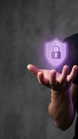 Male hand presenting glowing purple cybersecurity shield with padlock icon representing data protection and digital security solutions for business.