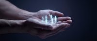 Male hands cupped together holding glowing translucent human figures representing protection, care, and support in business or healthcare concept.